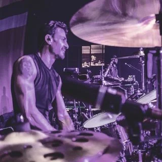 Brad Wilk showcasing his drumming skills with intense passion.