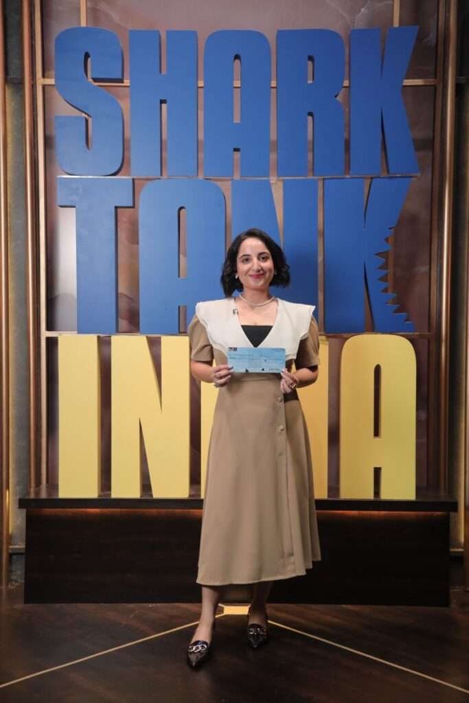 Priyasha Saluja holding a check on Shark Tank India.